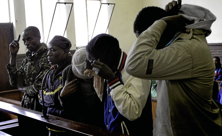 Five suspects accused of eating human flesh try to hide their faces in the Estcourt Magistrate's Court. File photo.