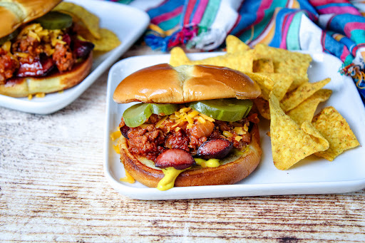 Hot Dog on the Round on a plate with chips.