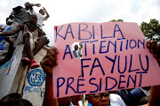 Supporters of the runner-up in DRC's presidential election, Martin Fayulu, hold a sign before a political rally in Kinshasa on January 11 2019.