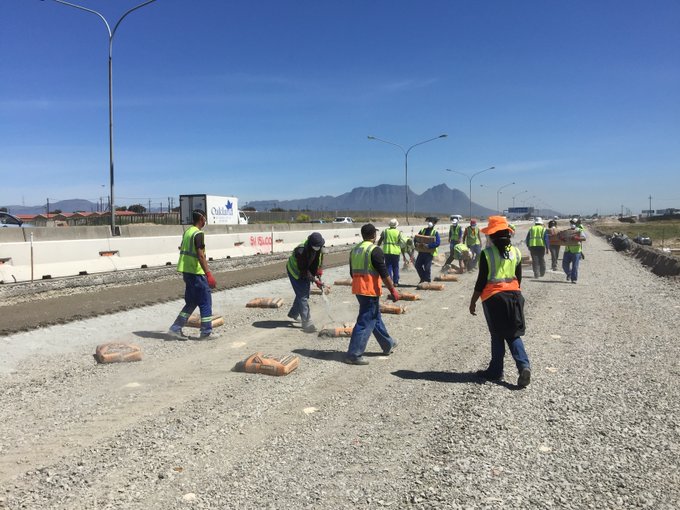 Workers prepare recycled concrete to be mixed into the new road.