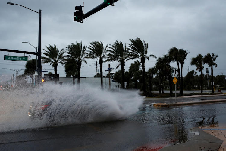 A car drives by a flooded street ahead of the expected arrival of Hurricane Nicole, in Daytona Beach, Florida, US, November 9, 2022.