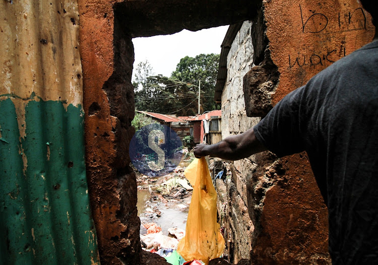 A man is seen throwing of garbage material into the Nairobi River in Kangemi on March 26, 2024.