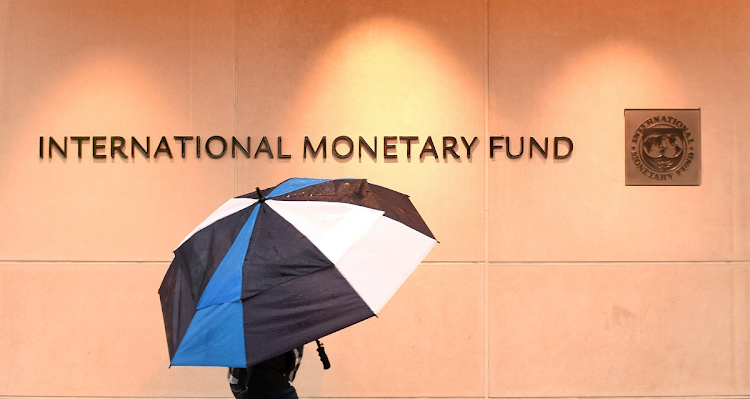 A pedestrian with an umbrella walks past the International Monetary Fund headquarters in Washington, DC, US. Picture: 123RF/BUMBLEDEE