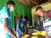 Junior Mbelekane and his granny Phumzile Mnisi are assisted by local youth to produce face masks.   /  Mandla Khoza