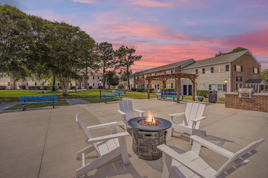 exterior of apartment building with tan siding, brick detailing, landscaping, fire pit, and walking paths 