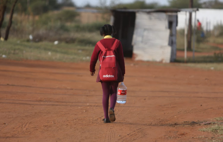 After joining the queue, a pupil walks home with a five-litre bottle of water donated to community members by Gift of the Givers at a clinic in Hammanskraal, Gauteng, on Tuesday.