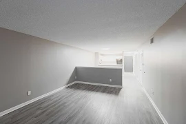 Open concept living and dining area with a breakfast bar to the kitchen and wood-inspired flooring throughout