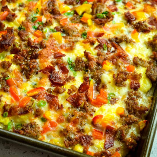 Breakfast Pizza that has crispy bacon, sausage, sweet peppers, and onions on a freshly baked pizza crust, all topped with oodles of melted provolone and Pepper Jack Cheese.
