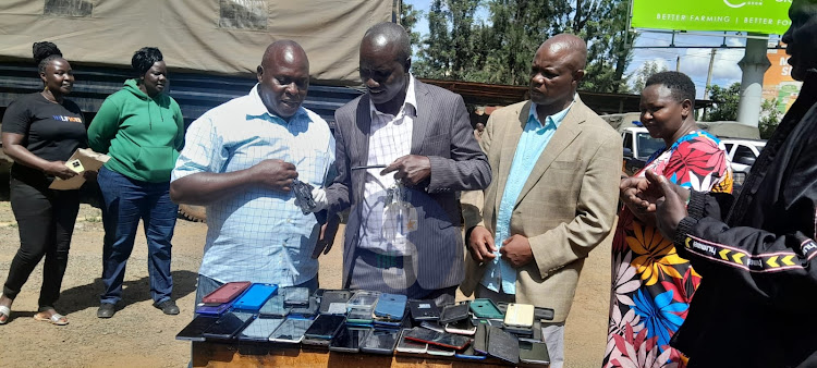 Uasin Gishu county police commander Benjamin Mwanthi (c) and DCI boss Daniel Muleli (L) examining a gun recovered from suspects arrested in Eldoret on April 7, 2024