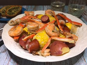 A one-pot meal with crab legs, prawns, smoked sausage, red potatoes, corn, and a lot of seasoning.