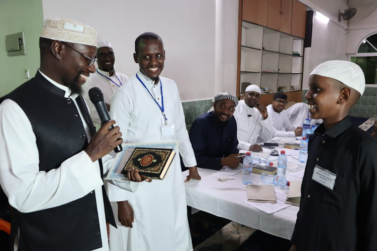 Kisumu Muslim Association chairman Shelkh Musa Ismail presents a copy of the Holly Quran to the winner of the second edition of Quran competition Abdulrahman Hassan Daud in Kisumu, May 3, 2024.