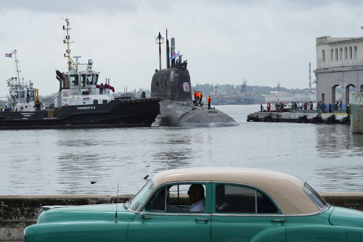 A vintage car passes by as Russian nuclear-powered cruise missile submarine Kazan docks in Havana’s bay, Cuba, June 12, 2024.