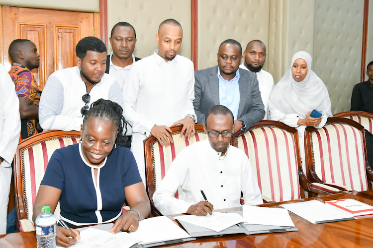 Emergency Plus Medical Services (E-Plus) Managing Director Susan Ng’ong’a and Director of Health Aden Hussein append their signature after an agreement between E-plus and the county of Garissa. Looking on are county leaders.