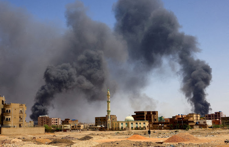 A man walks while smoke rises above buildings after aerial bombardment, during clashes between the paramilitary Rapid Support Forces and the army in Khartoum North, Sudan, May 1, 2023.