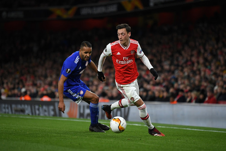 Mesut Ozil of Arsenal is challenged by Youssef El Arabi of Olympiakos during the UEFA Europa League round of 32 second leg match at Emirates Stadium on February 27, 2020 in London