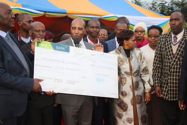 Nyandarua Governor Francis Kimemia, Deputy governor Cecilia Mbuthia and Agriculture executive James Karitu (L) present a Sh60 million cheque to farmers' groups at Wakirogo Stadium in Kipipiri on Tuesday, January 28, 2020