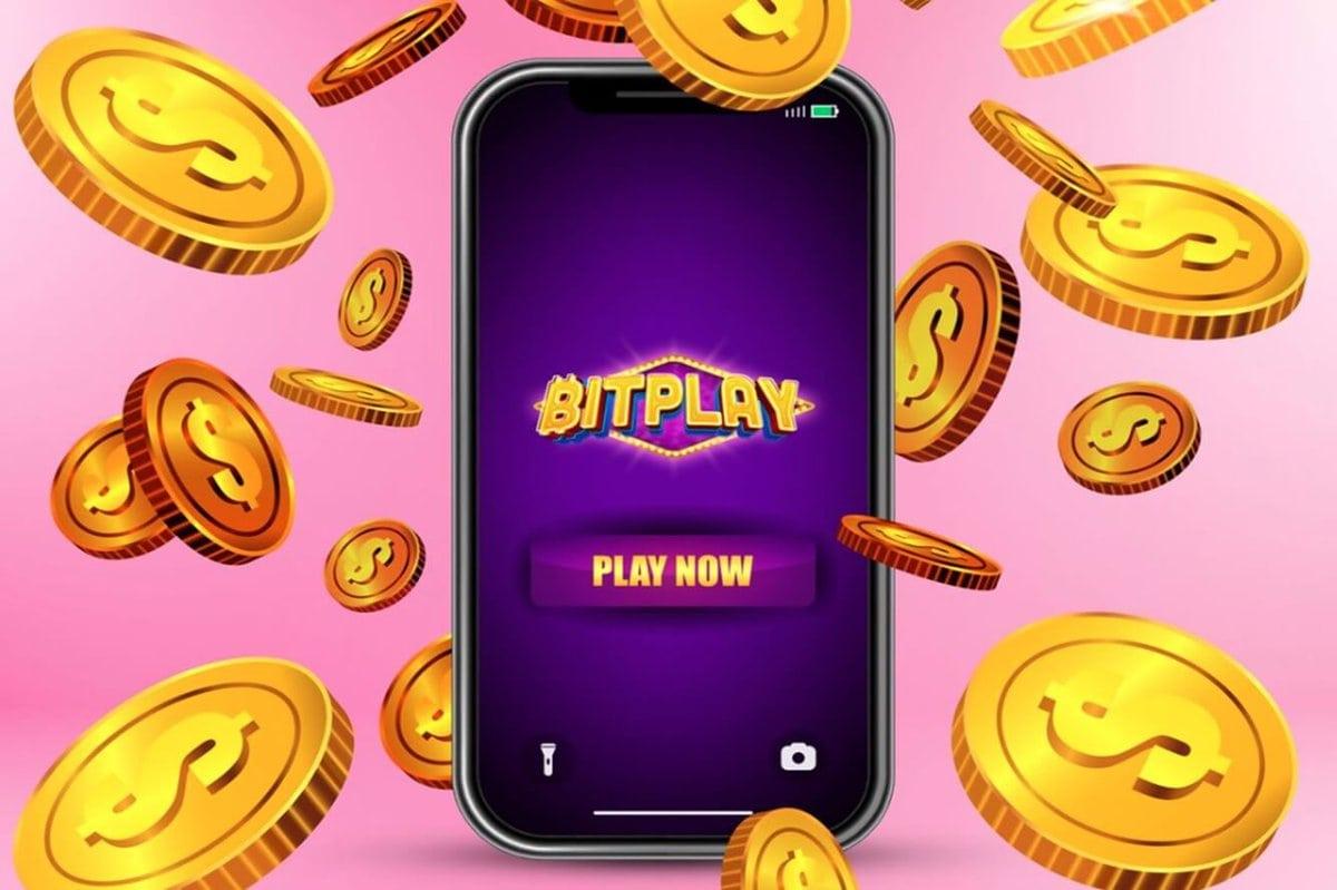 Bitplay casino logo on mobile phone with dollar coins around on pink background