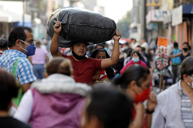 A man carrying a sack on his head walks along a crowded commercial street amid the outbreak of coronavirus disease (COVID-19) in downtown Mexico City, Mexico December 19 2020.