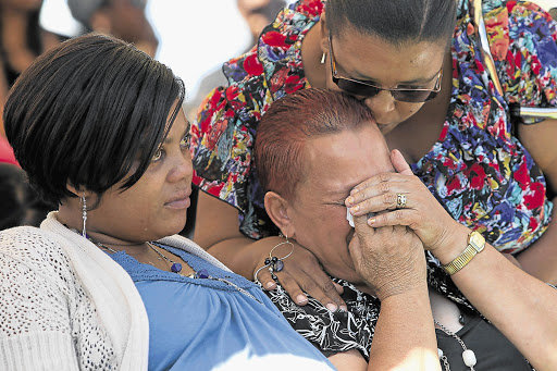 Belinda Jacobs, the grief-stricken wife of alleged gang member Johnny Jacobs, is comforted by relatives at his funeral yesterday