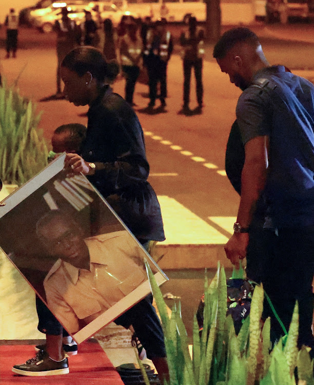 A family member of Angola's former President Jose Eduardo dos Santos carries a picture of him at Luanda international airport, in Angola, August 20 2022. Picture: SIPHIWE SIBEKO/REUTERS