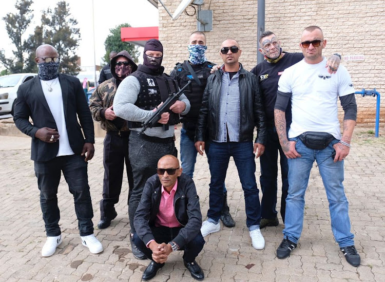 Nafiz Modack wearing a leather jacket and sunglasses standing third from right after a court appearance in Gauteng along with his bodyguards and associates.