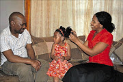 FAMILY BOND: Inako Kom, 4, being helped by her parents Welcome Nkabi and Ntombokhanyo Kom-Nkabi to wear  her new hearing aid   at her home in Delft, Cape Town. 
      PHOTO: UNATHI OBOSE