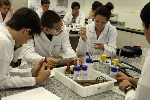 Imagem mostra estudantes em uma laboratório de ciências.