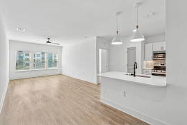 Bright and spacious apartment interior featuring a kitchen, large windows, and open living area.
