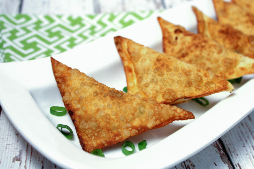 Cheese appetizers with chicken, green onion, and bacon on a white plate.