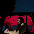 Una persona sentada en un coche durante la noche. El interior está iluminado en color rojo.