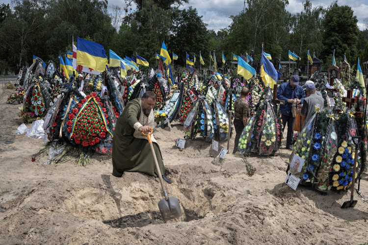 A priest shovels during a funeral for Ukrainian serviceman Mykhailo Tereshchenko, who was killed in a fight during Russia's invasion in the Donbas region, in Kyiv, Ukraine, on June 14 2022.