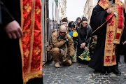 People kneel during the funeral of Yuriy Dadak-Ruf and Taras Kryt, killed due to artillery shelling in the Luhansk region, as Russia's invasion of Ukraine continues, in Lviv, Ukraine, on April 9 2022. 