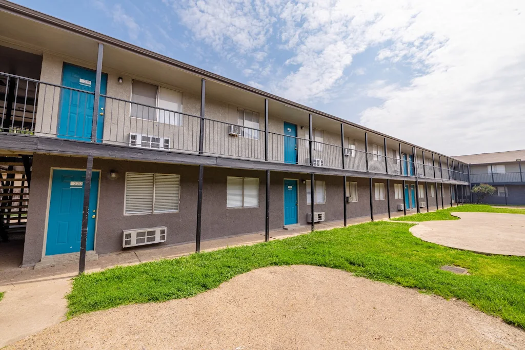 Two story apartment building with two-toned gray stucco siding and green space between 