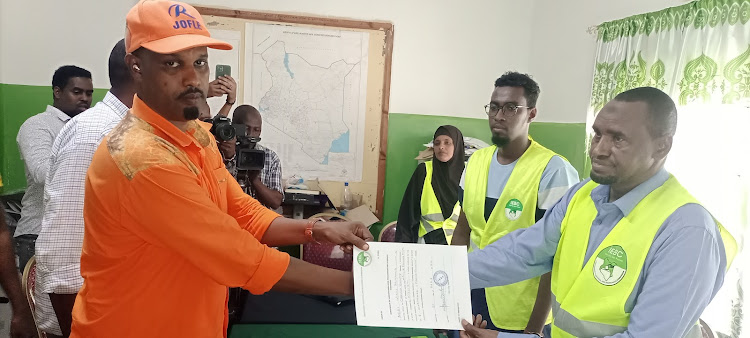 Garissa Township ODM parliamentary candidate Nasir Dolal receives his certificate form Garissa Township returning officer Abdi Yunis after he was cleared on Tuesday, May 31.