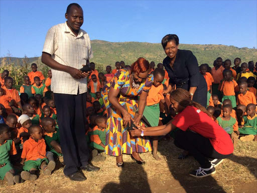 Meru Women Rep Florence Kajuju and the County Assistant Director of Education Lucy Mbae Red Cross official Daisy Kawira fit a shoe to a pupil at KK Muthangene in Tigania East during the anti jigger campaign where 17,000 pupils benefitted from shoes in Meru County