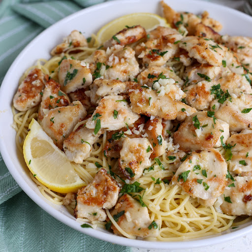 A scrumptious and easy Chicken Scampi recipe made with lightly breaded chicken bites, garlic, white wine, lemon juice, and parsley all in a bed of pasta topped with freshly grated Parmesan Cheese.