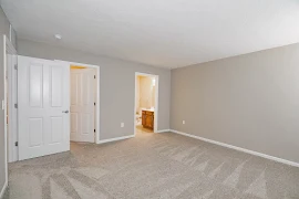 Apartment bedroom with view of attached bathroom and closet