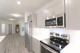 Kitchen with white countertops, stainless steel appliances, gray cabinets, wood finished flooring, and view of living area