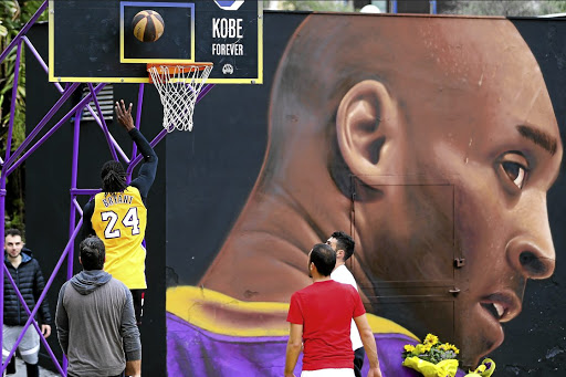 A group of boys play basketball, in the basketball court dedicated to the memory of the basketball player Koby Bryant, in the Montedonzelli district in Naples. In the background, the mural by artist Jorit Agoch dedicated to Kobe Bryant. /Marco Cantile/LightRocket via Getty Images