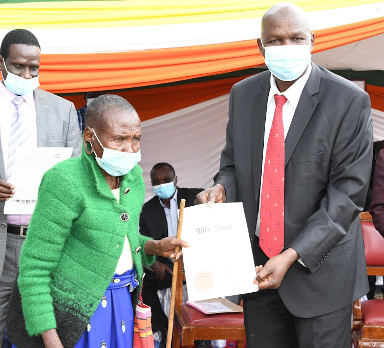 Baringo Governor Stanley Kiptis (right) hands over 21,000 title deeds outside his Kabarnet town offices on Friday.