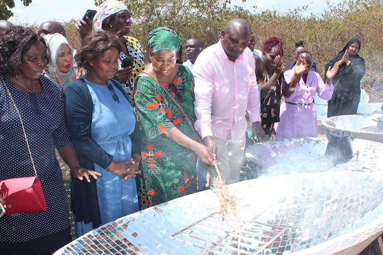 Tessie Mudavadai and Ahadi Kenya CEO Stanley Kamau light a fire using a parabolic solar cooker on October 22, 2022.