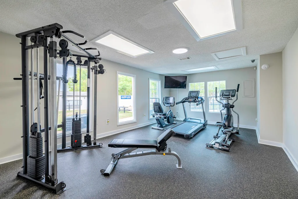 Fitness center with three cardio machines, a mounted tv, and a cable weight machine 