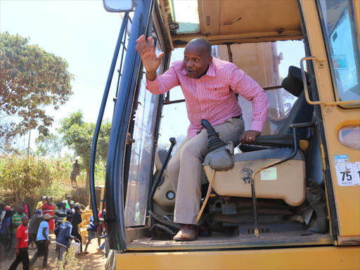 Tharaka Nithi senator Kithure Kindiki waves at residents as he alights from an excavator after he commisioned Sh.1 billion road in Maara constituency to improve tea,coffee and horticulture delivery.