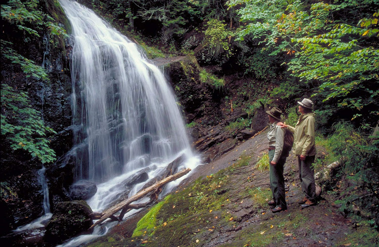 Hikers admire a waterfall in New Brunswick, Canada. 