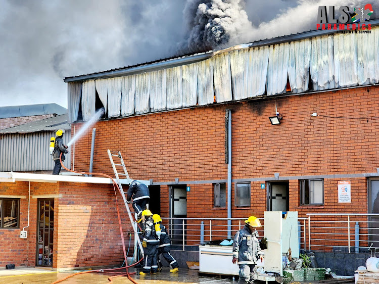 Firefighters bring a fire under control at a warehouse in Springfield, Durban