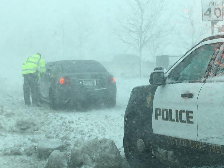 A policeman talks to a driver as snow clogs the roads in Lone Tree, Colorado, US in this March 13, 2019.