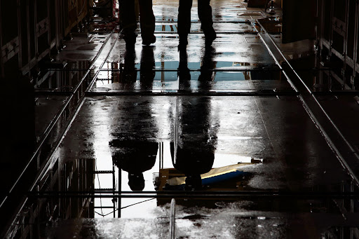 Workers are reflected in a puddle of rainwater on the Total SA FPSO CLOV, a floating production, storage and offloading (FPSO) vessel built for the company's Clov oil field project in Angola, under construction at the Daewoo Shipbuilding & Marine Engineering Co. (DSME) shipyard in Geoje, South Korea, on Tuesday, June 25, 2013. An index of South Korean manufacturers expectations for July fell to 78 from 82 in the previous month, the lowest level since March, the Bank of Korea said in a statement today.