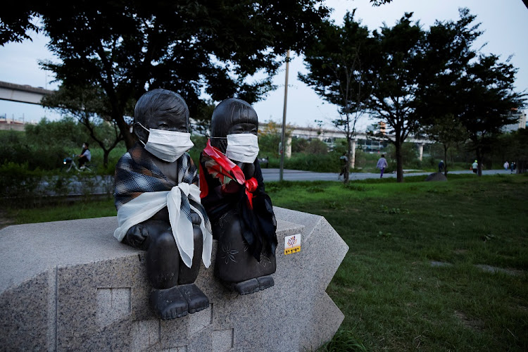 A sculpture of brother and sister is pictured with protective masks on, as people stroll in a park amid the coronavirus disease (COVID-19) pandemic in Seoul, South Korea.