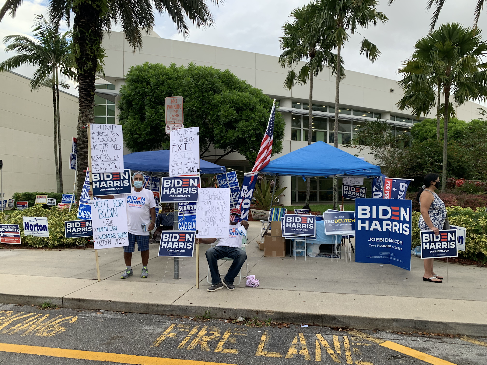 Democratic tent and volunteers at NW Regional Library during early voting holding up signs. Photo by Logan Rubenstein