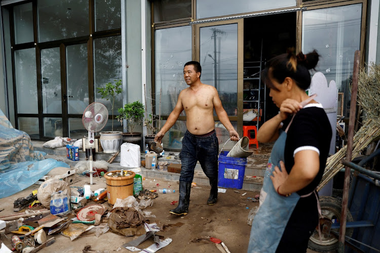 Li Yujie, 47, looks on as Zhang Hongwei, 48, sorts muddied items at their flood-stricken hardware store after the rains and floods brought by remnants of Typhoon Doksuri, in Zhuozhou, Picture: TINGSHU WANG